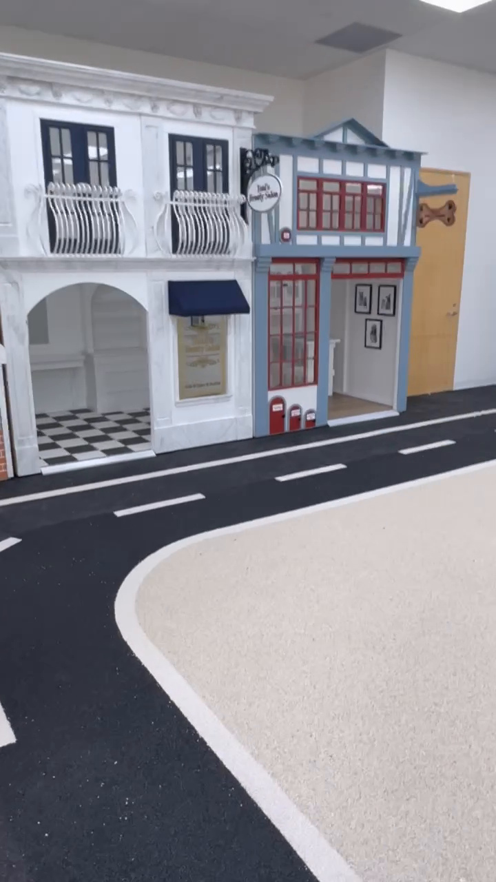 White road markings and light rubber flooring beside playhouses at Beyond Play in Barrie